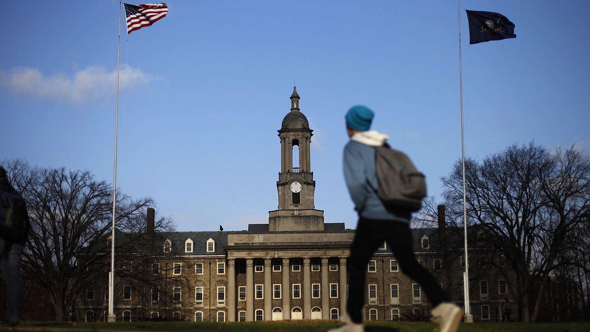 Image: A students walks in front of the Old Main building on the Penn State