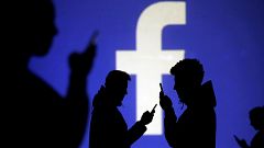 Image: People on phones next to a Facebook logo projection on March 28, 201