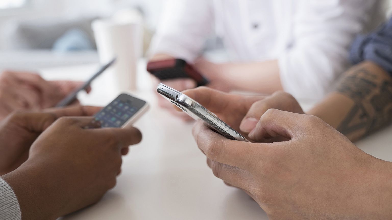 Close up of friends texting with cell phones at table