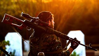 Image: A fighter with the Syrian Democratic Forces holds a rifle as he atte