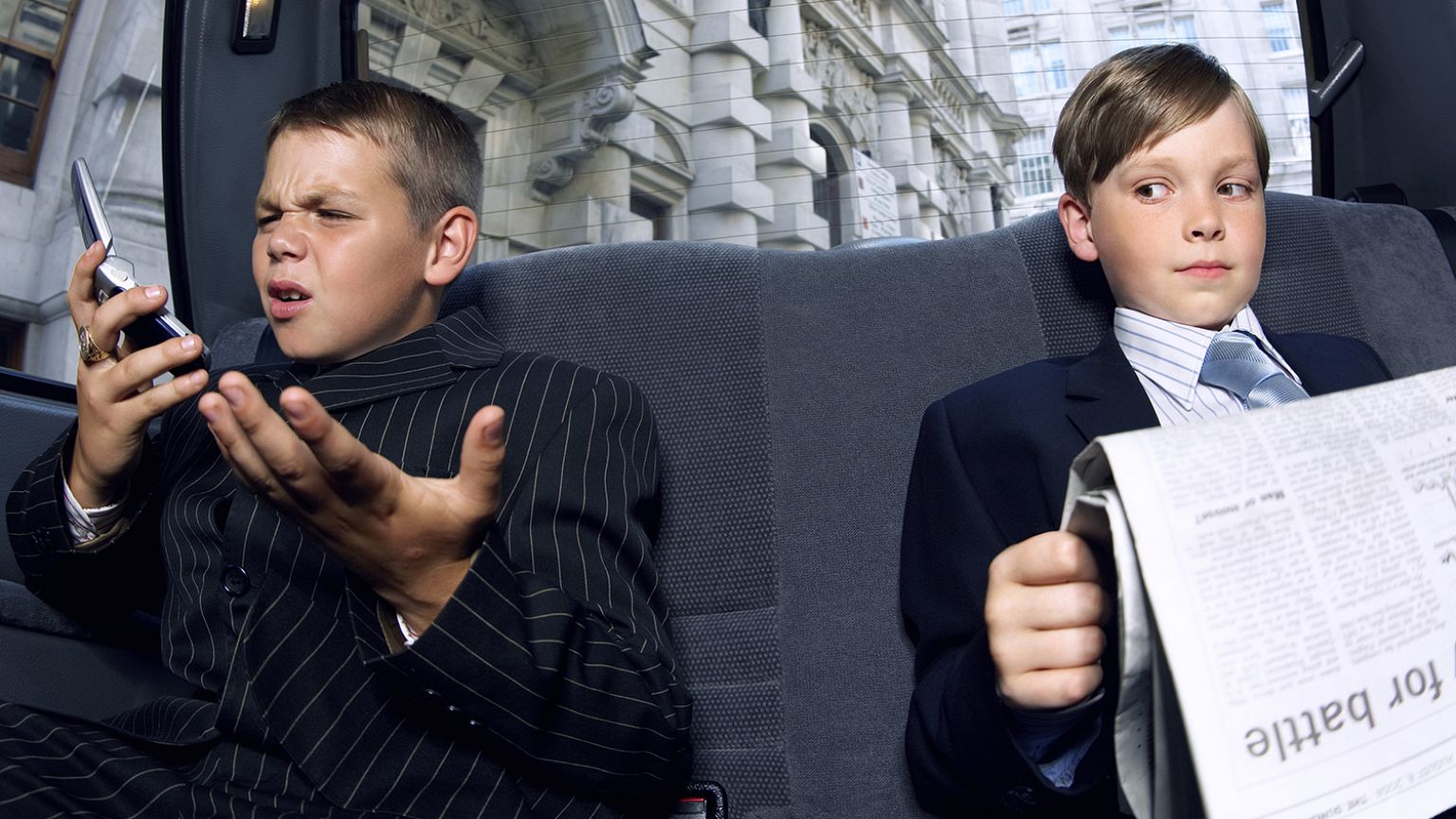 Boys dressed as businessmen in back of a car.