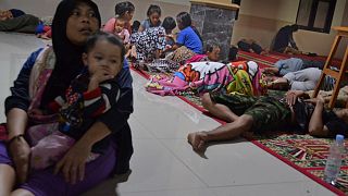 Image: Residents sit inside a mosque as they evacuated following high waves