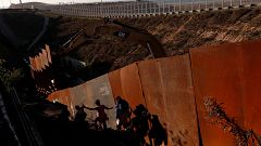 Image: Migrants climb down a steep hill after giving up on trying to climb 