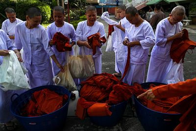 Devotees in white robes return saffron robes after ending their novice monkhood.