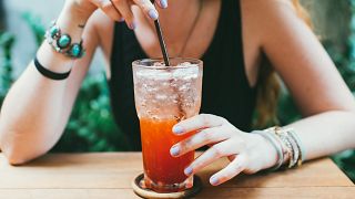 Midsection Of Woman Having Cocktail On Table