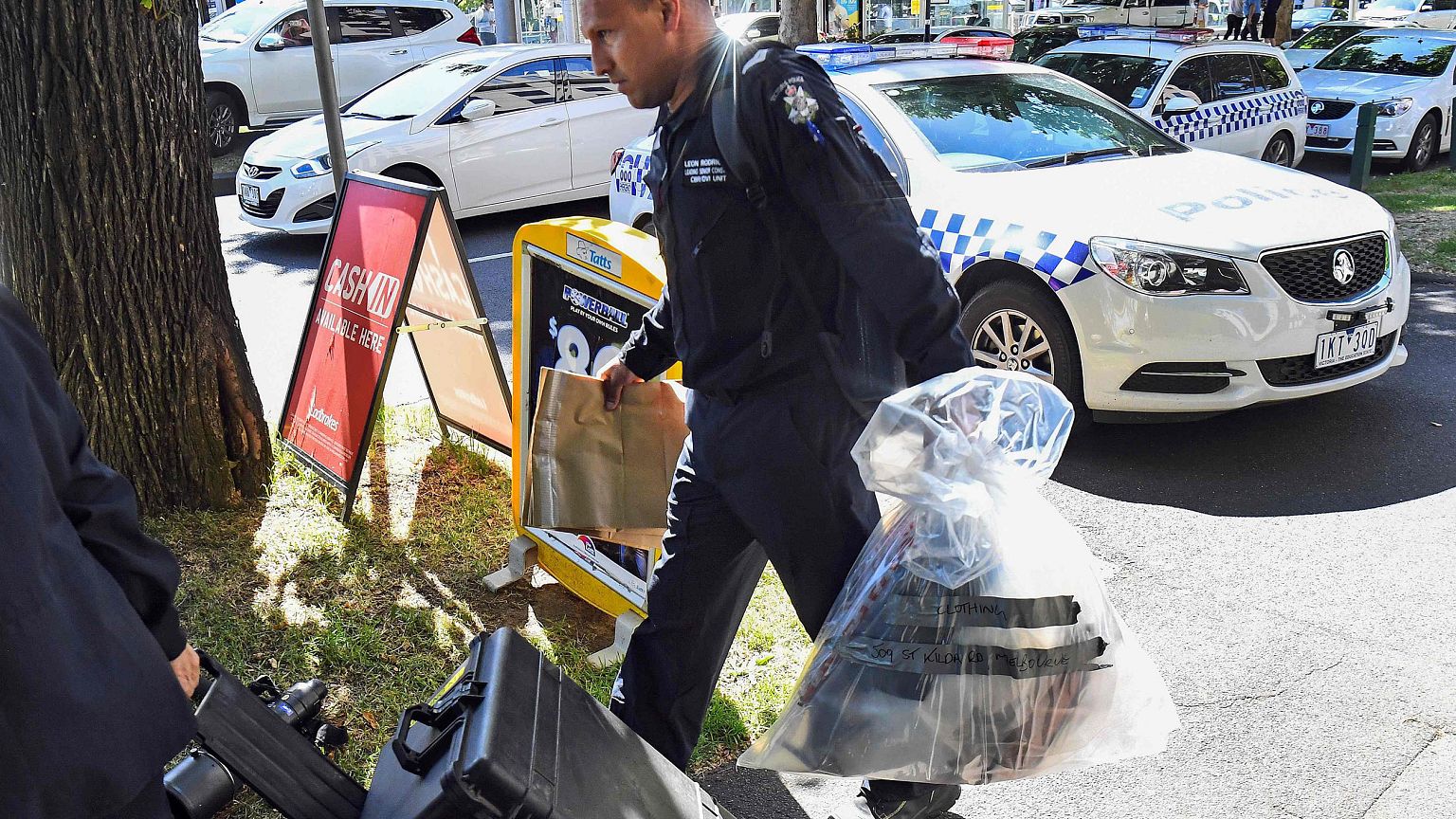 Image: A Victoria Police forensic officer carries items to be loaded into a