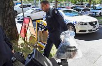Image: A Victoria Police forensic officer carries items to be loaded into a