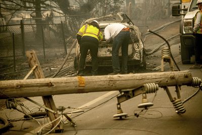 Eric England, right, searches through a friend\'s car near a downed utility pole after the Camp fire blazed through California on Nov. 10, 2018.