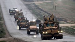 Image: A convoy of US military vehicles rides in Syria's northern city of M