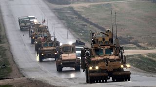 Image: A convoy of US military vehicles rides in Syria's northern city of M