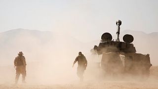 Image: Hezbollah fighters walk near a tank in western Qalamoun, Syria