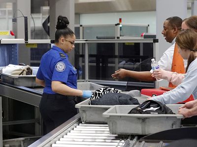 A Transportation Security Administration employee helps air travelers submit their bags for inspection at Hartsfield Jackson Atlanta International Airport Monday, Jan. 7, 2019, in Atlanta.