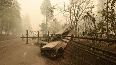 Image:  fallen power line is seen on top of burnt out vehicles on the side 