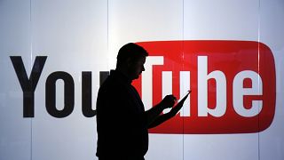 Image: A man stands in front of YouTube's logo at an office in London