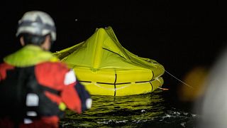 Image: Rescuers drop a life raft after a rubber dingy capsized off the coas