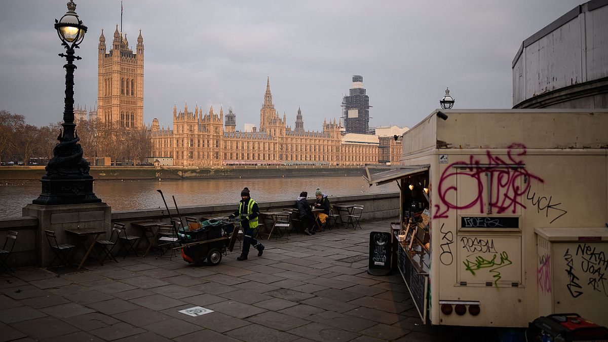 Image: A street cleaner walks near the Houses of Parliament