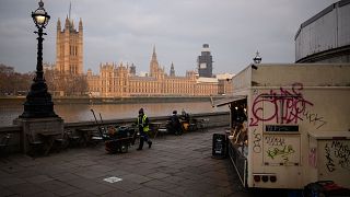 Image: A street cleaner walks near the Houses of Parliament