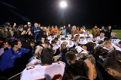Bremerton assistant football coach Joe Kennedy, obscured at center in blue, is surrounded by players in prayer in Bremerton, Washington, on Oct. 16, 2015.