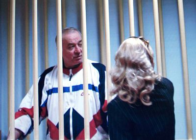 Sergei Skripal speaks to his lawyer from behind bars seen on a screen of a monitor outside a courtroom in Moscow.