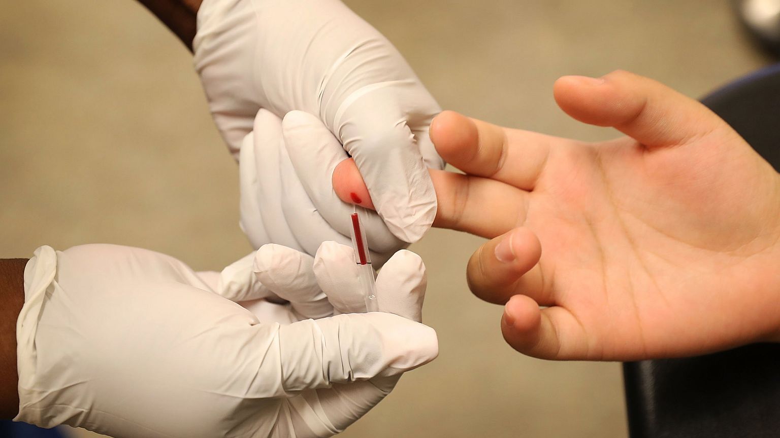 Image: A medical assistant draws blood from a patient on National HIV Testi