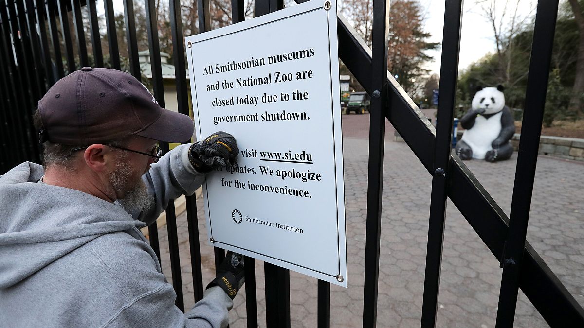 Image: A Smithsonian National Zoo employee removes a closure sign after the