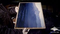 Image: A Russian police officer holds "The Ai-Petri, Crimea" painting after