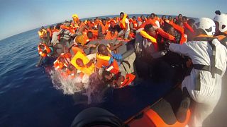Helfer springen ins Wasser, um Flüchtlinge zu retten