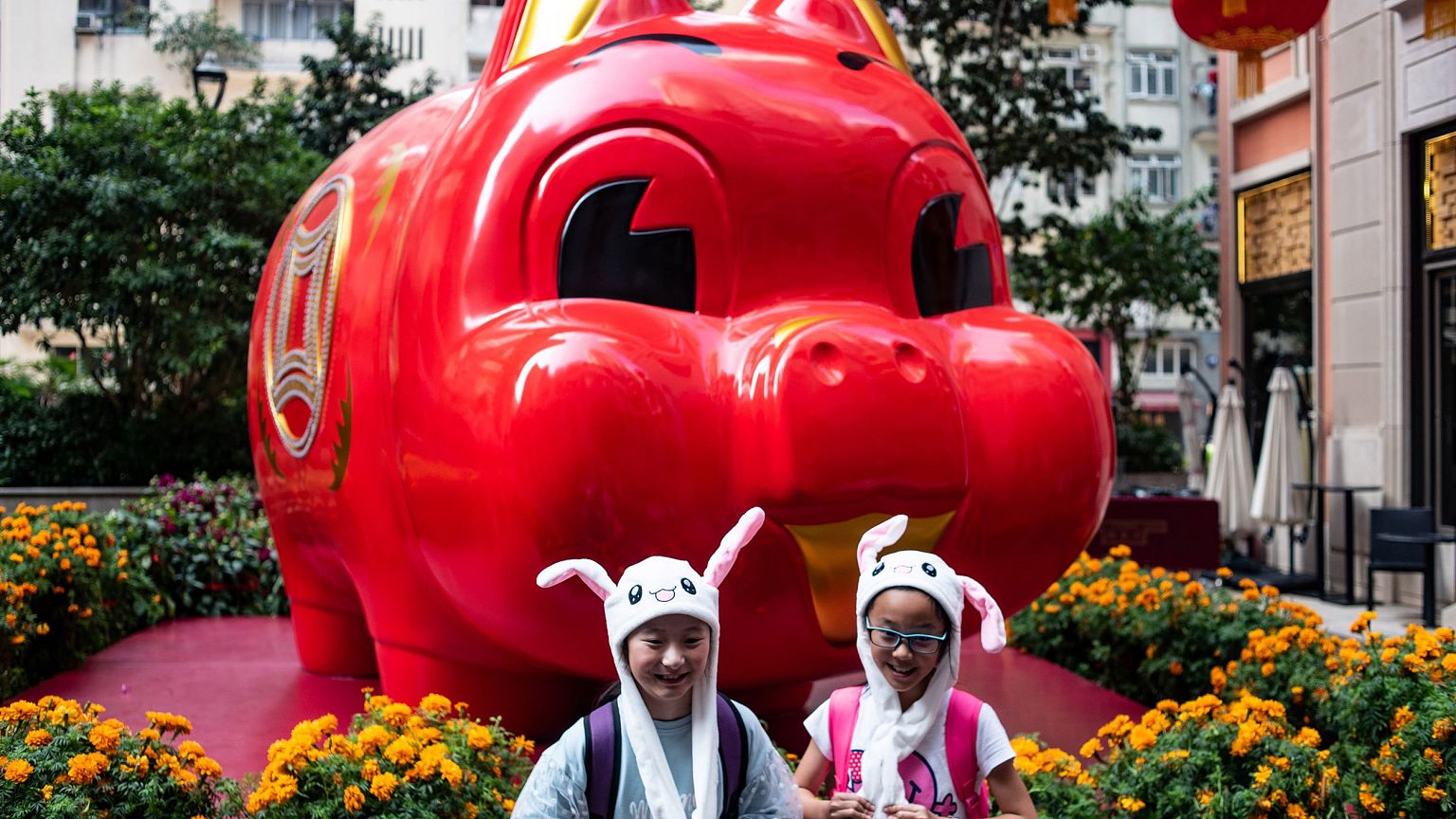 Image: Children in animal hats pose in front of a pig giant pig installatio