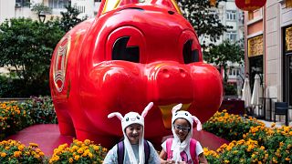 Image: Children in animal hats pose in front of a pig giant pig installatio