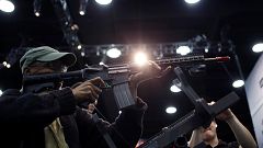 Image: An attendee holds an AR-15 style gun on the exhibit floor at the Nat