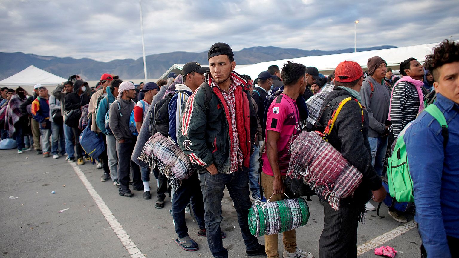 Image: Migrants wait in line to get into buses during their journey towards