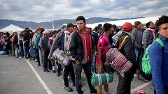 Image: Migrants wait in line to get into buses during their journey towards