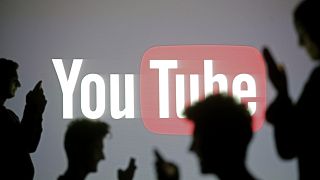 Image: Silhouette of people on mobile phones in front a YouTube sign