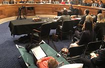 A woman testifies from a cot at Senate hearing on managing pain during the