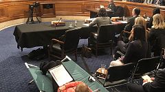 A woman testifies from a cot at Senate hearing on managing pain during the 