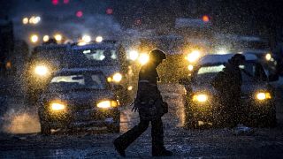 Image: A pedestrian walks across Sprague Avenue as snow falls in Spokane, W