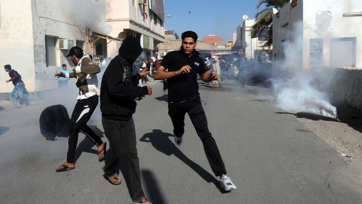 Image: Bahraini protestors run for cover after