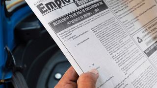 Image: A man reads an advertisement of the vacancy for hangmen on a newspap