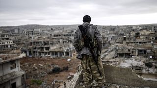 Musa, a 25-year-old Kurdish marksman, stands atop a building as he looks at