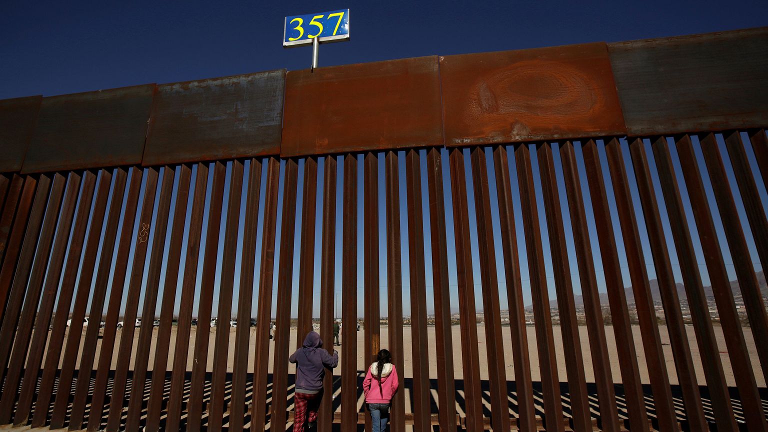 Image: Children peek through the border fence at Anapra neighbourhood in Ci