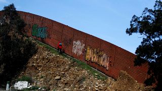 Image: A person walks along the U.S.-Mexico border fence in Tijuana on Feb.