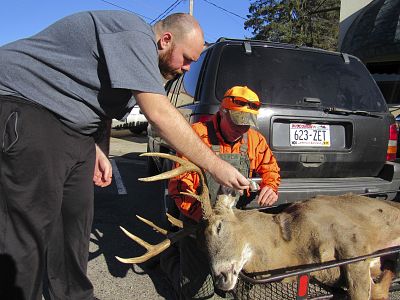 Daniel Crook, right, looks at a photo Dan Ruhland took of Crook\'s nine point deer  in downtown Plain, Wisconsin, on Nov. 21, 2016.