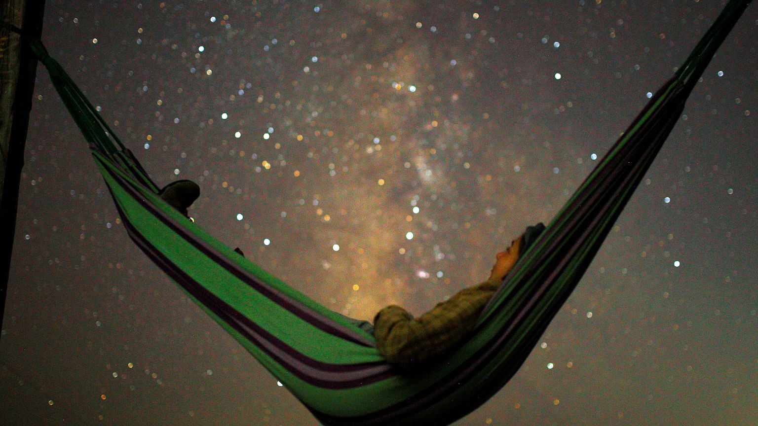 A girl lies in hammock as she looks at the milky way during the peak of Per