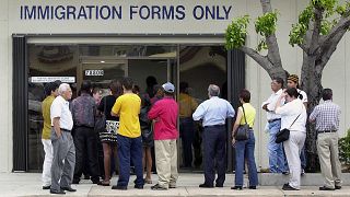 Image: A line forms near the entrance of the Immigration