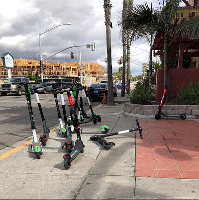 Scooters left on a street corner near the beach in San Diego.