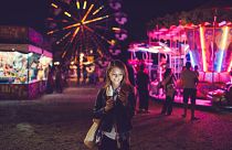 Image: Smiling woman texting at the amusement park