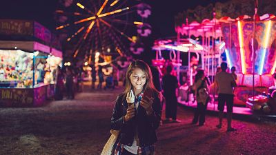 Image: Smiling woman texting at the amusement park Image: Smiling woman texting at the amusement park