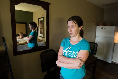 Tammy Basinger stands with her 1-year-old daughter in the motel room where they lived for weeks after being forced to vacate Allen Benedict Court.