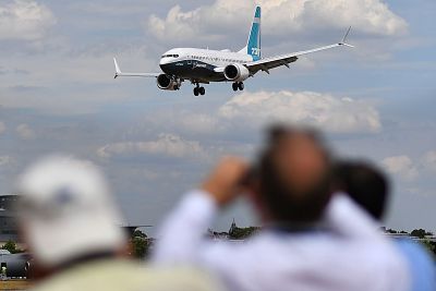 Visitors watch as a Boeing 737 Max lands during an air show.