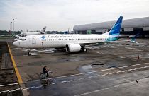 Image: An official rides a bicycle as he passes Garuda Indonesia's Boeing 7